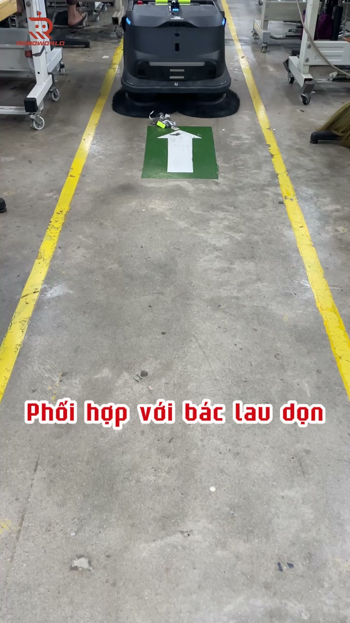 Sàn xưởng may sau khi MT1 đi qua — sợi vải, chỉ vụn được hút sạch dọc lối đi, giữ mặt sàn khô ráo và an toàn.